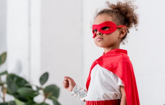 Portrait of cute little african american child in red superhero costume and mask